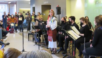 Photo from "For Ukraine: An Artistic Tribute" showing seated musicians and a performer in traditional clothing